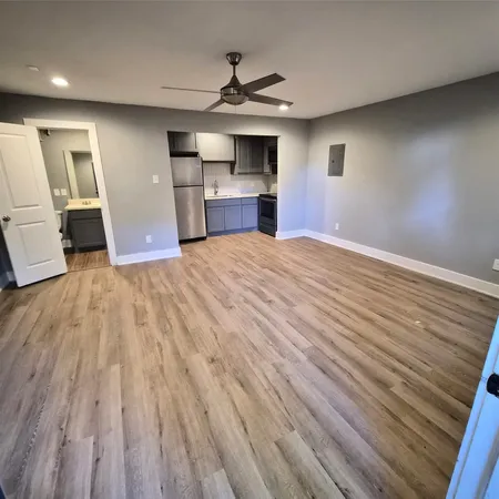 a view of empty room with wooden floor and kitchen view