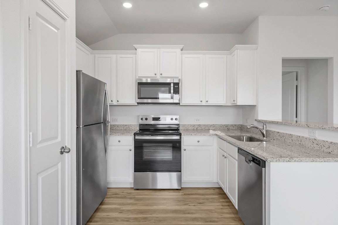 18420 Stellers Sea Street Elgin, TX 78621 - Photo 4 of 7 a kitchen with stainless steel appliances granite countertop a stove a refrigerator and a sink