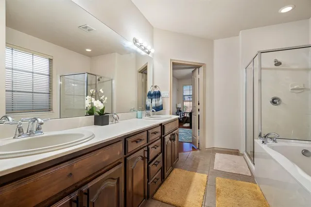 a spacious bathroom with a bathtub double sink and mirror