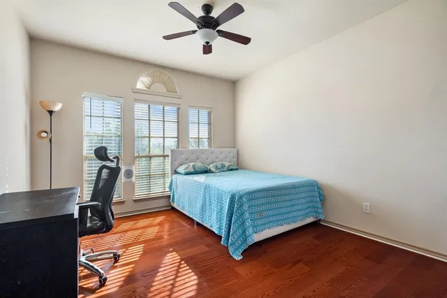 a bedroom with a bed windows and wooden floor