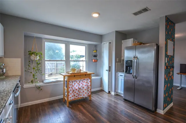 a kitchen with stainless steel appliances granite countertop a refrigerator and wooden floor