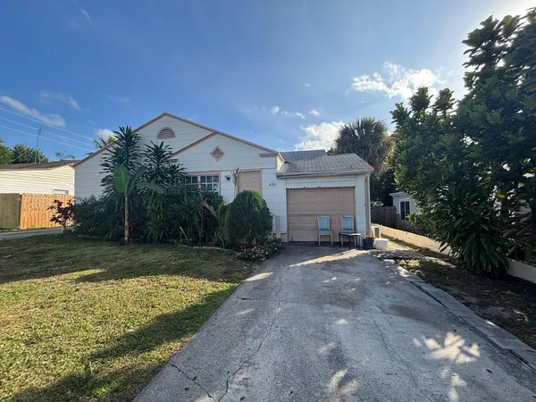 a view of a house with a yard and large tree