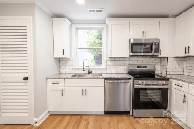 a kitchen with stainless steel appliances granite countertop a stove a sink and a microwave