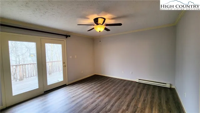 a view of empty room with wooden floor and fan