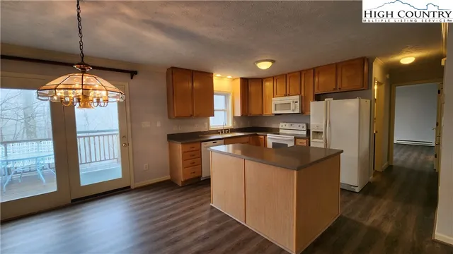 a kitchen with stainless steel appliances granite countertop a refrigerator a sink dishwasher a stove and a dining table with wooden floor