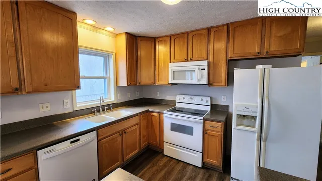 a kitchen with stainless steel appliances granite countertop a sink a stove a refrigerator cabinets and wooden floor