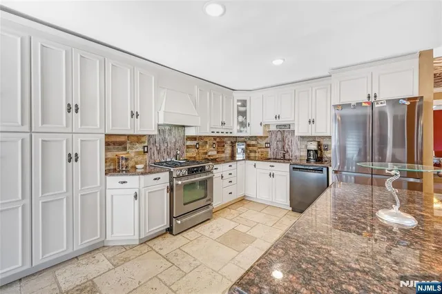 a kitchen with granite countertop white cabinets and stainless steel appliances