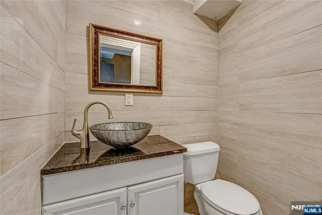 a bathroom with a granite countertop toilet a sink and mirror