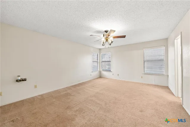 an empty room with windows and chandelier fan