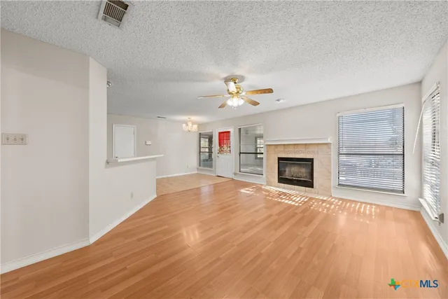 an empty room with windows fireplace and a kitchen view