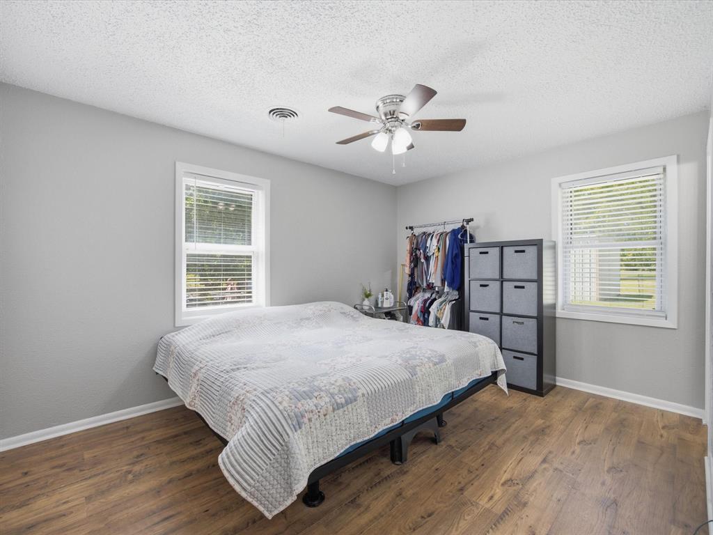 714 Decatur Street Bowie, TX 76230 - Photo 9 of 16 Primary Bedroom with light gray walls, vinyl plank flooring, and Ceiling Fan
