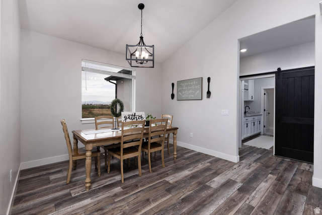 186 West 580 North Redmond, UT 84652 - Photo 14 of 74 Dining space featuring lofted ceiling, a barn door, dark wood-type flooring, and suspended lighting
