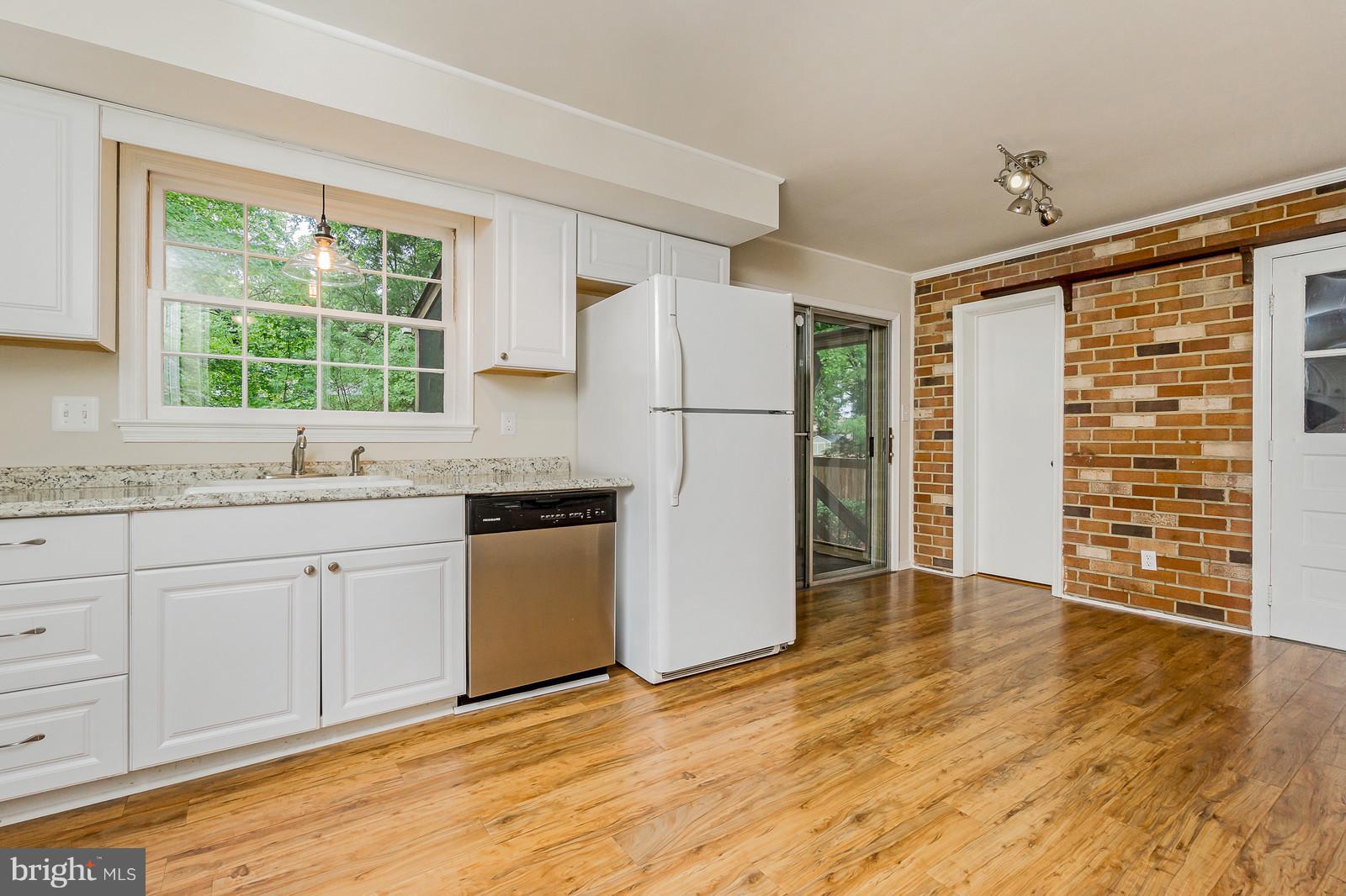 6723 Huntsman Boulevard Springfield, VA 22152 - Photo 6 of 32 a kitchen with granite countertop a refrigerator a sink and white cabinets