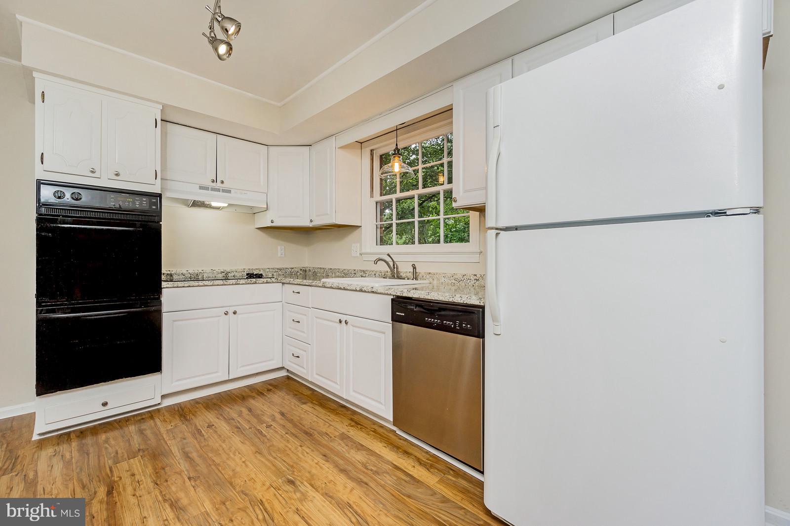 6723 Huntsman Boulevard Springfield, VA 22152 - Photo 7 of 32 a kitchen with granite countertop a refrigerator sink and white cabinets