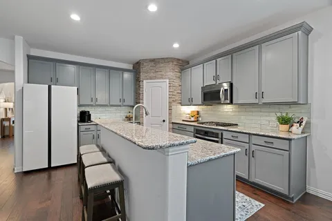 a kitchen with kitchen island granite countertop a stove a sink a refrigerator a center island and cabinets