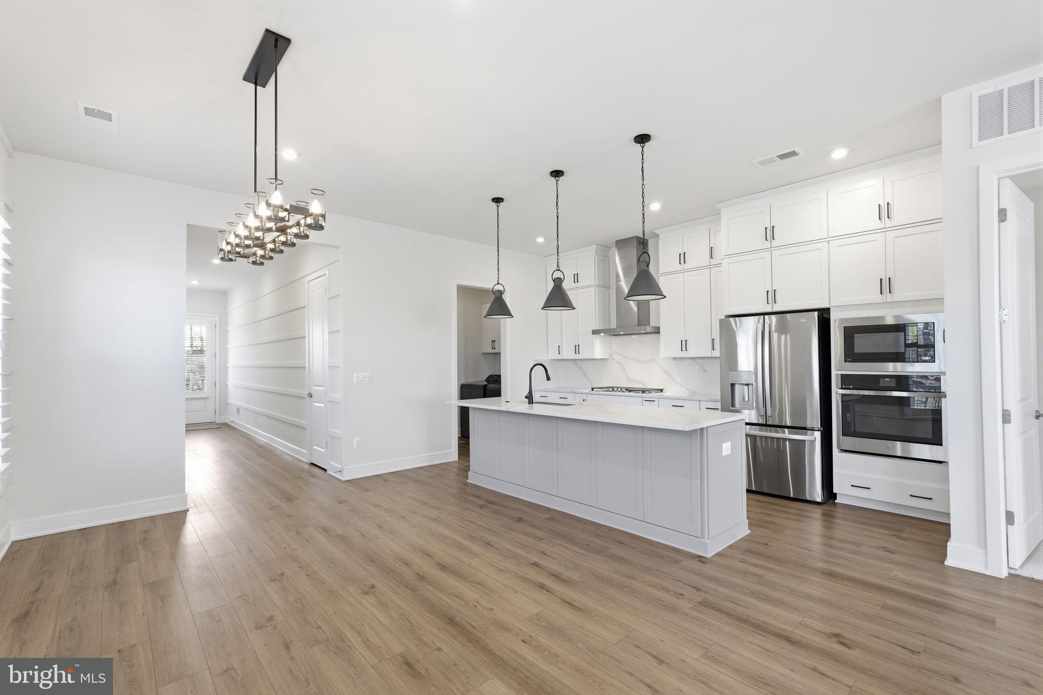 14679 Grand Cru Loop Gainesville, VA 20155 - Photo 5 of 41 a kitchen with stainless steel appliances wooden floor and chandelier