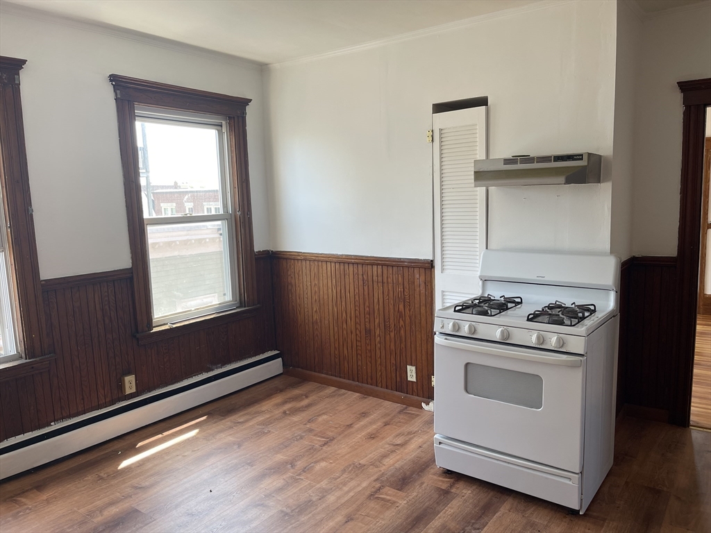 25 Perkins Street, Unit 3 Salem, MA 01970 - Photo 5 of 8 a kitchen with a stove and a wooden cabinet
