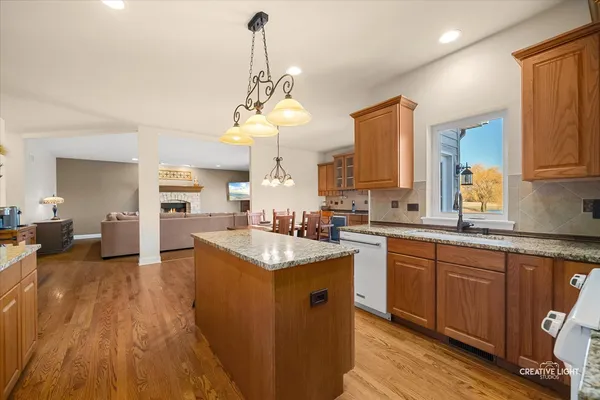 a kitchen with stainless steel appliances granite countertop a sink dishwasher a stove and a dining table with wooden floor