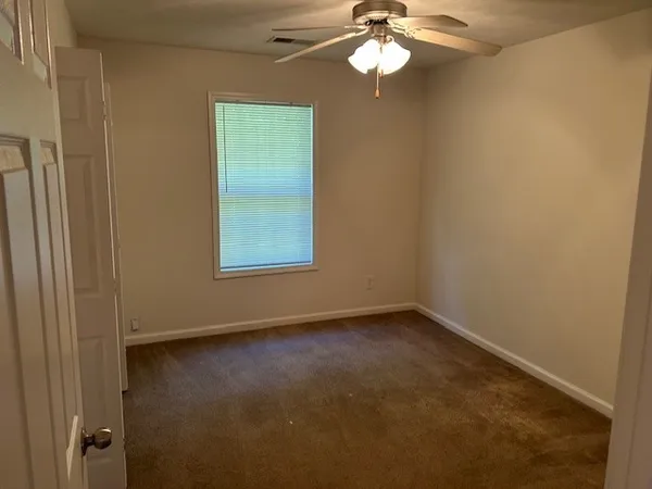 an empty room with a chandelier fan and windows