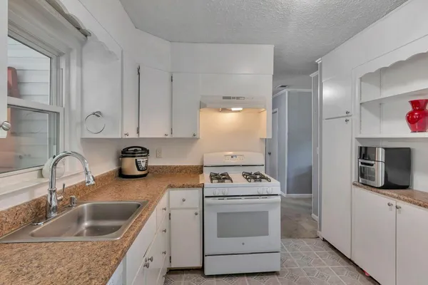 a kitchen with granite countertop a sink stove and cabinets