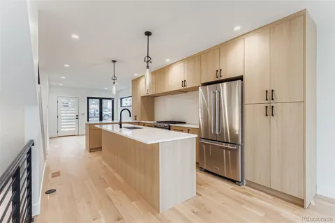 a kitchen with stainless steel appliances granite countertop a refrigerator a oven and a sink with wooden floor