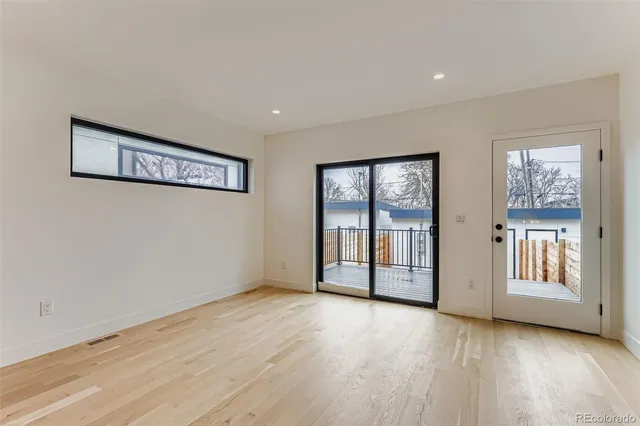 a view of an empty room with glass door and wooden floor