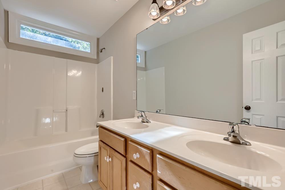 6040 Big Sandy Drive Raleigh, NC 27616 - Photo 20 of 28 a bathroom with a granite countertop sink a toilet a shower and a mirror