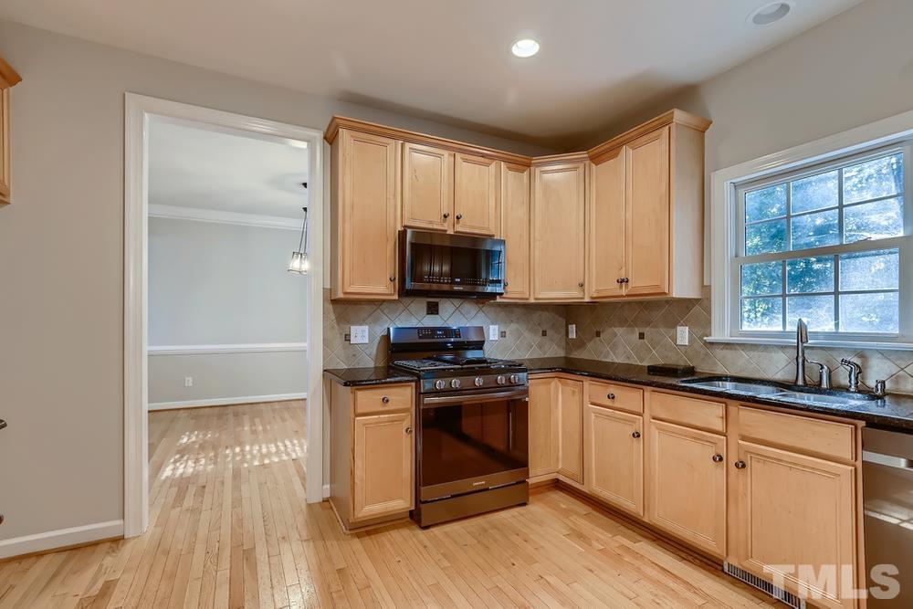 6040 Big Sandy Drive Raleigh, NC 27616 - Photo 9 of 28 a kitchen with granite countertop a stove a sink and a microwave