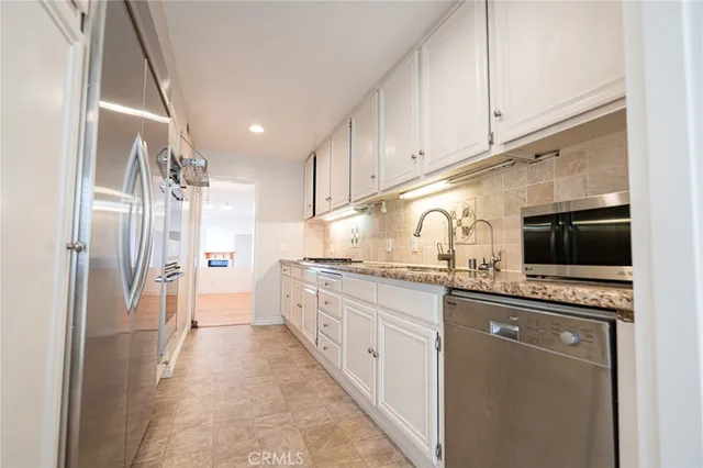 a kitchen with stainless steel appliances a sink stove refrigerator and cabinets