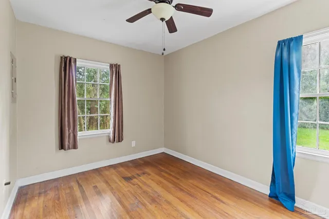 a view of empty room with wooden floor and fan