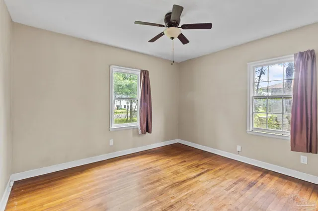 a view of empty room with wooden floor and fan