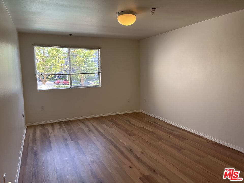 4501 Cedros Avenue, Unit 135 Sherman Oaks, CA 91403 - Photo 15 of 19 an empty room with wooden floor and windows