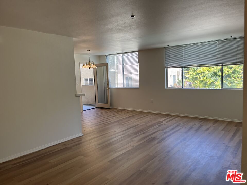 4501 Cedros Avenue, Unit 135 Sherman Oaks, CA 91403 - Photo 16 of 19 an empty room with wooden floor and windows