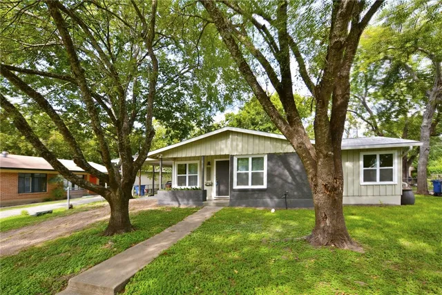 a front view of a house with a yard and large trees