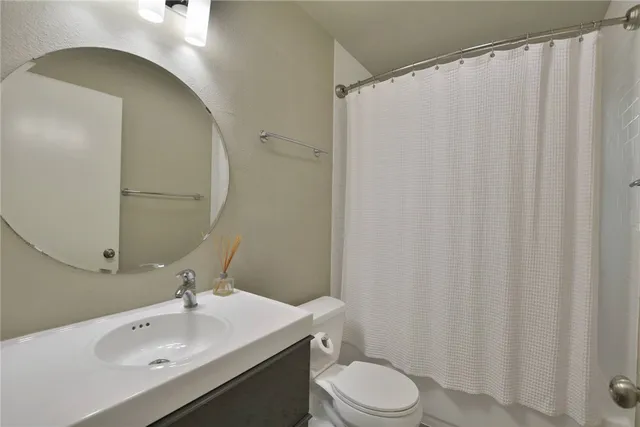 a bathroom with a sink a toilet and shower curtain