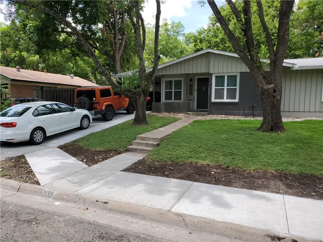 a front view of a house with a yard and potted plants