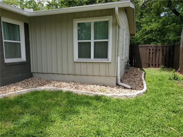 a view of a house with a small yard and a large tree