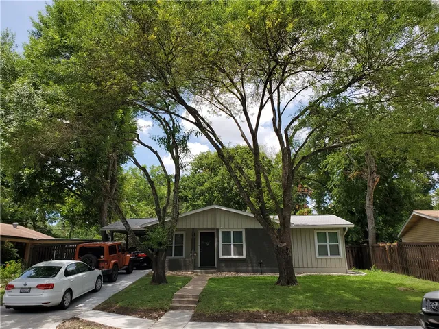 a front view of a house with a garden and trees