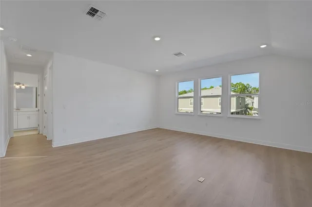 an empty room with wooden floor and windows