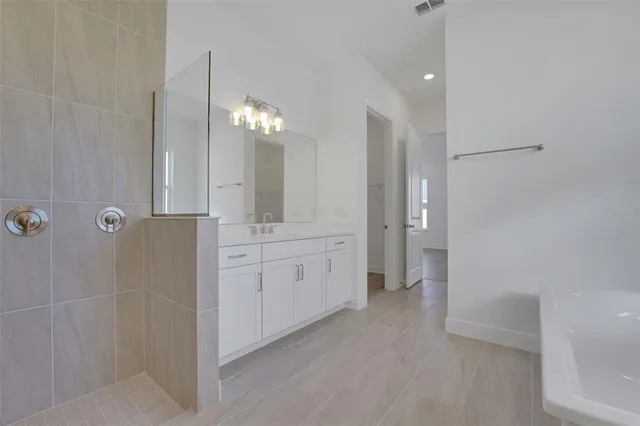 a spacious bathroom with a double vanity sink a large mirror and shower