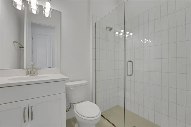 a bathroom with a toilet a sink a mirror a vanity and shower