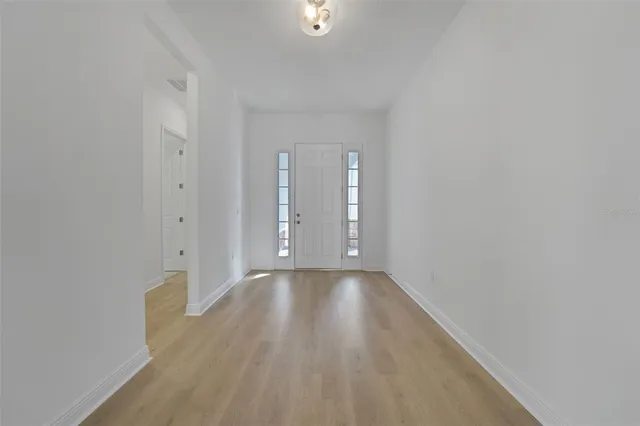 a view of an empty room with wooden floor and closet
