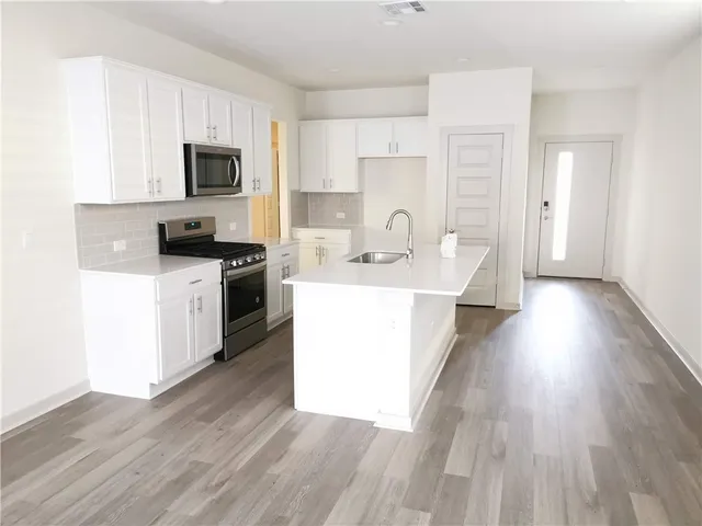 a large white kitchen with wooden floor