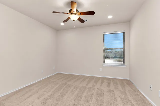 an empty room with a window and a ceiling fan
