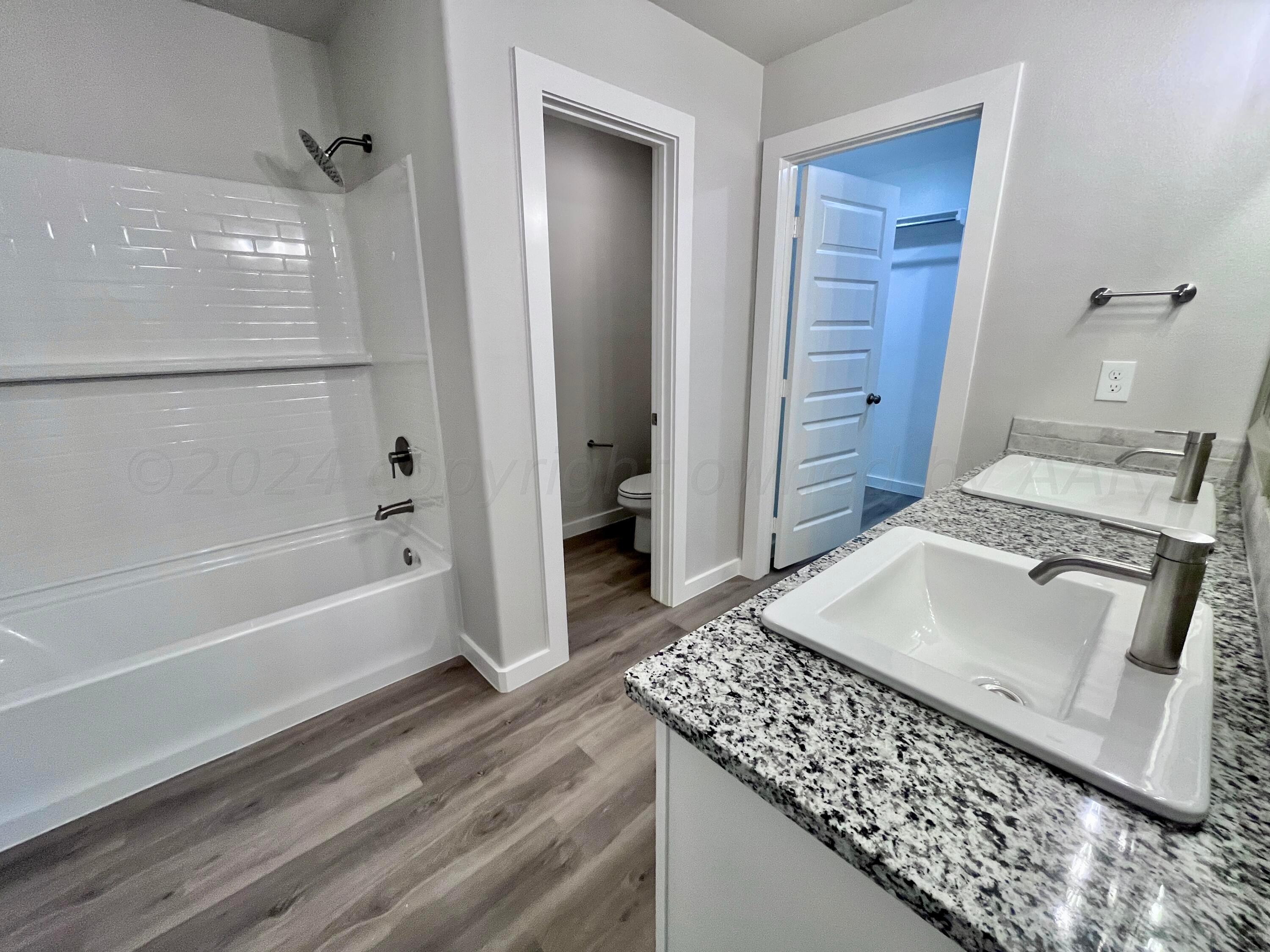 3103 Swenson Street Amarillo, TX 79124 - Photo 10 of 23 a bathroom with a granite countertop sink a toilet and shower