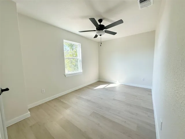 an empty room with a window and a fan