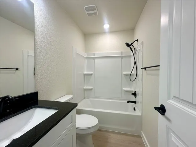 a bathroom with a granite countertop sink toilet mirror and shower