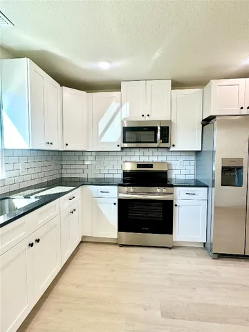 a kitchen with granite countertop white cabinets and stainless steel appliances