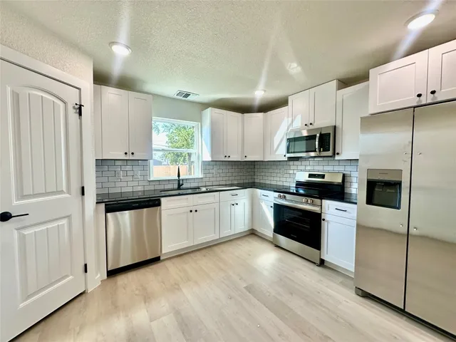 a kitchen with stainless steel appliances granite countertop a stove a sink and a refrigerator
