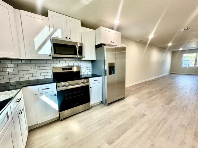 a kitchen with stainless steel appliances a stove a microwave and white cabinets